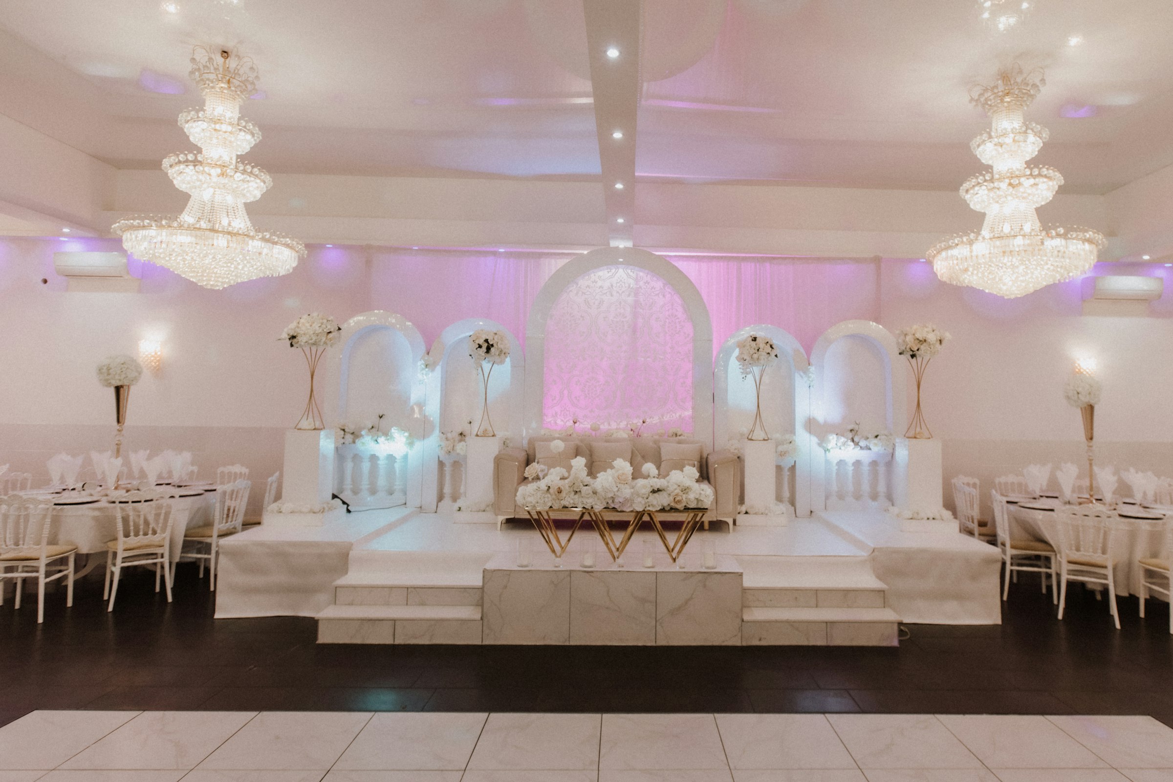 Wedding stage dressed in white with tiered chandeliers overhead