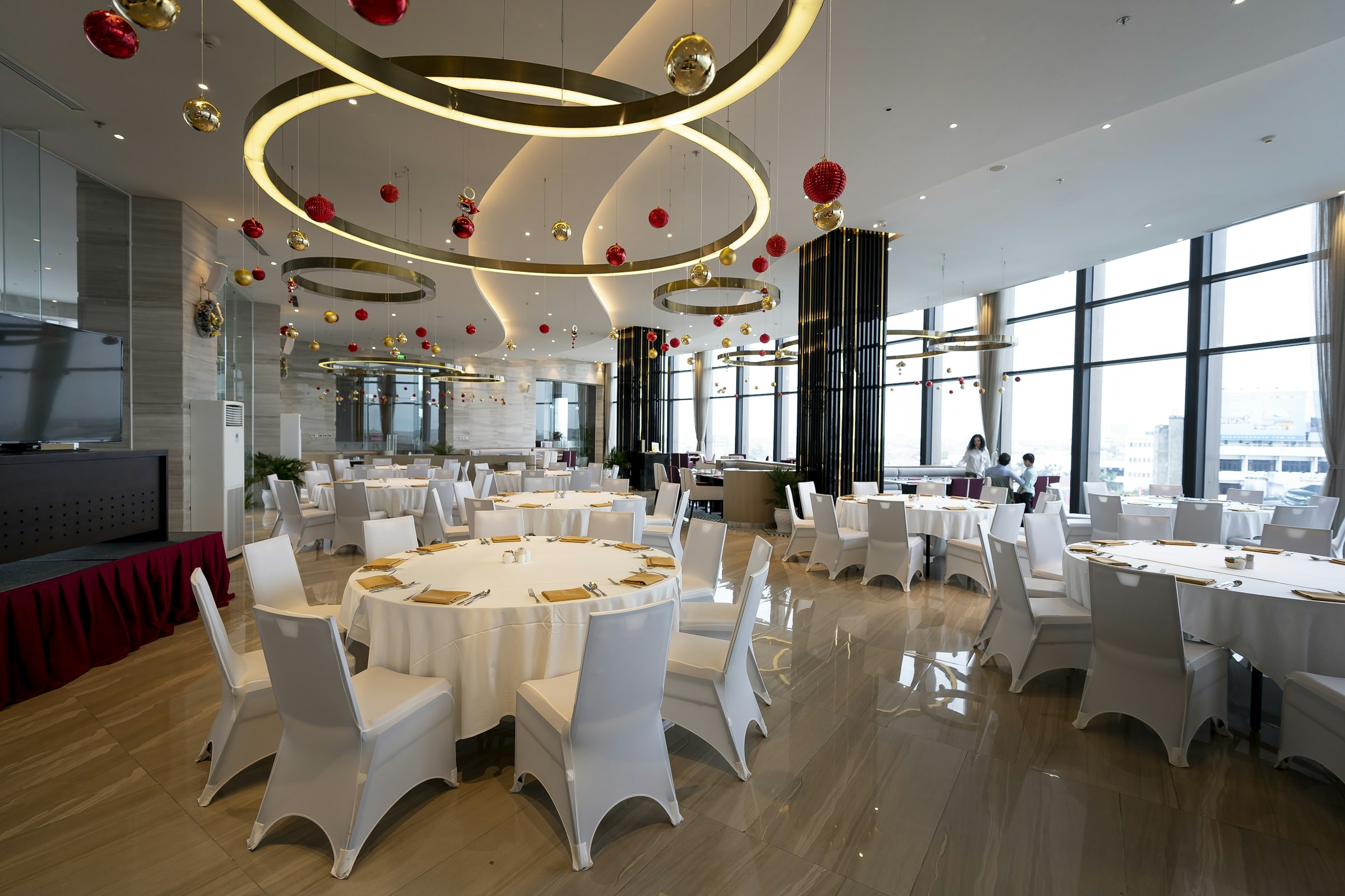 Airy modern banquet hall set with white chairs and round tables